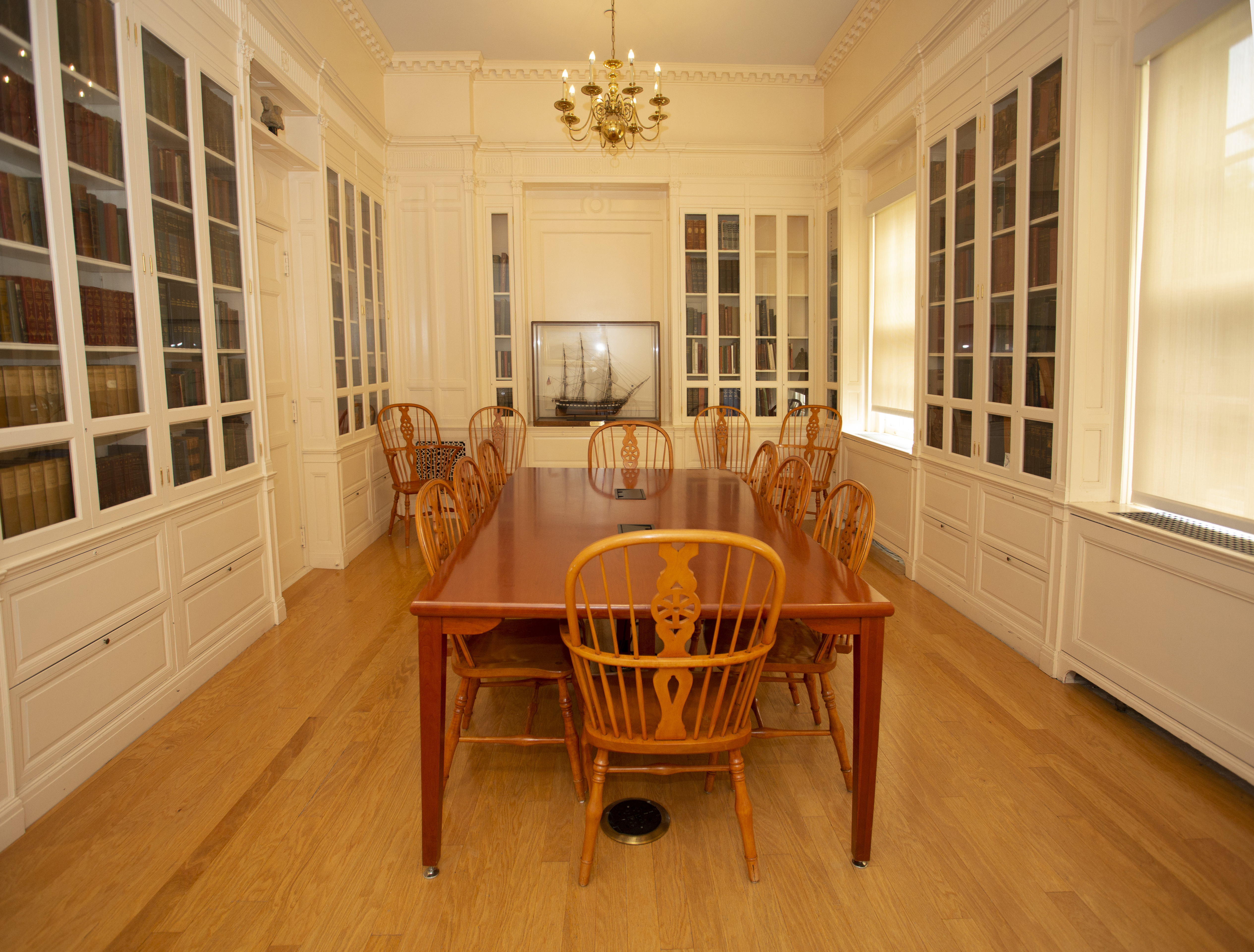 Annie B. Jennings Room showing a hardwood floor, enclosed book shelving, and a long rectangular wood table with chairs 