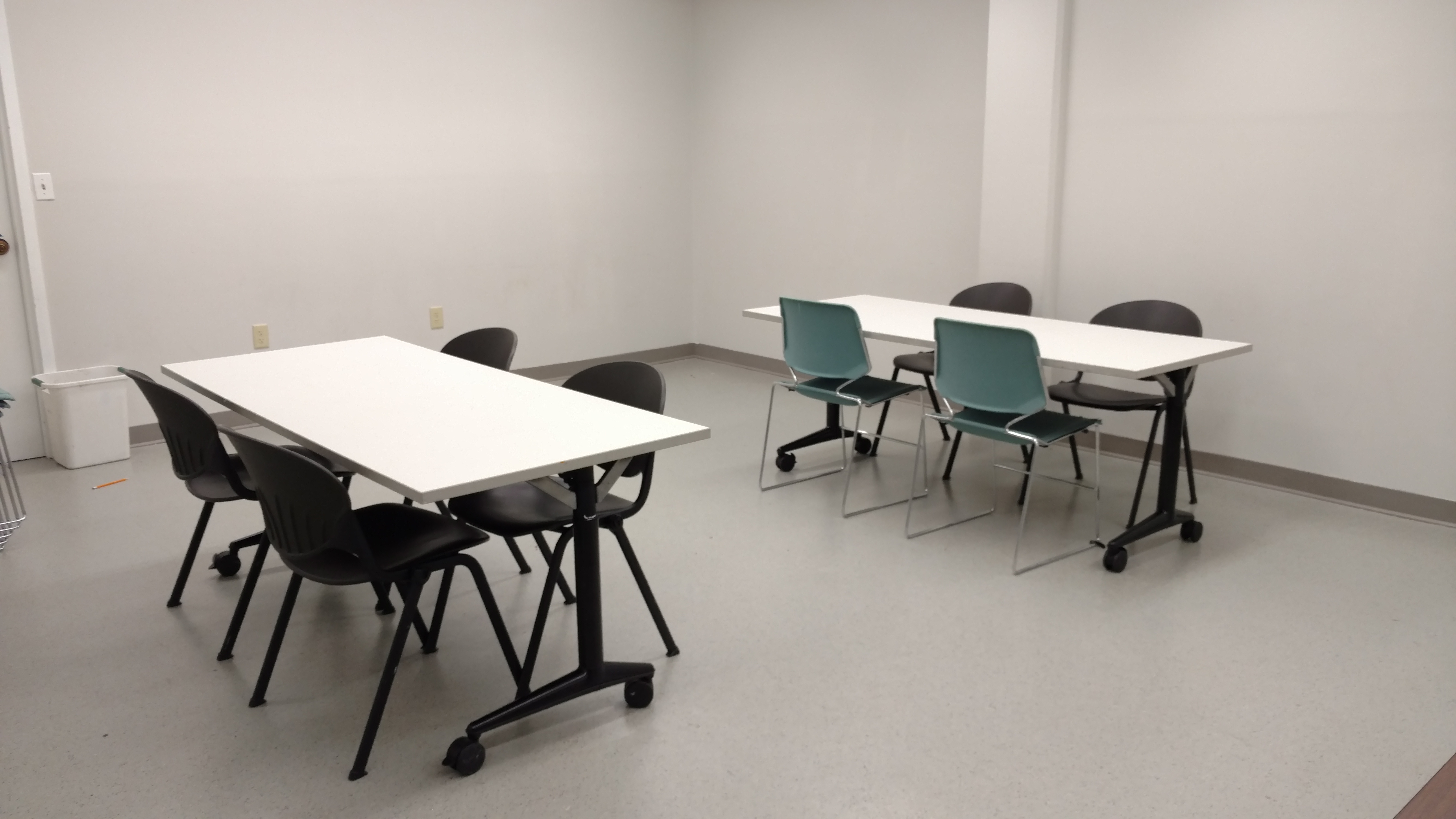 Small meeting room equipped with two rectangular tables with four chairs at each table