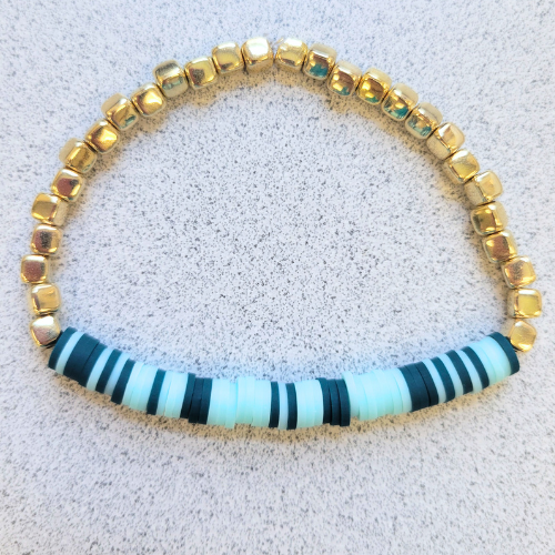 Bracelet reads "let it be" in morse code using dark blue beads for the letters, light blue beads for spaces, and gold beads for filler.
